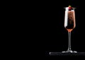 Elegant glass of pink rose champagne with raspberry on stick on black marble board on black background. Space for text Royalty Free Stock Photo