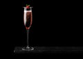 Elegant glass of pink rose champagne with raspberry on stick on black marble board on black background. Space for text Royalty Free Stock Photo