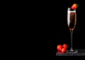 Elegant glass of pink rose champagne with strawberry on top and fresh berries on black marble board on black background. Space for Royalty Free Stock Photo