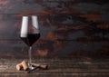 Elegant glass of red wine with corks and corkscrew on dark wooden background. Natural Light Royalty Free Stock Photo