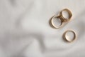 Elegant golden rings on white fabric, flat lay with space for text. Stylish bijouterie Royalty Free Stock Photo