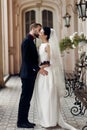 elegant gorgeous bride and stylish groom hugging kissing, sensual touch on background of old building. unusual luxury wedding