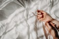 Elegant hands lie on the white bed sheet in the sunlight. Bed with white linens. The concept of a good morning, stress relief, Royalty Free Stock Photo