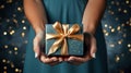 Elegant hands presenting a gift box wrapped in blue and gold ribbon, with a sparkling bokeh background, symbolizing a special