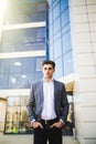 Elegant handsome young businessman while walking in front of office building, outdoors Royalty Free Stock Photo