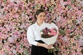 Elegant healthy woman smiling and holding colorful pink color flower bouquet on floral spring or summer background, studio fashion Royalty Free Stock Photo