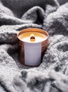 Elegant home decoration with wooden wick burning candle and knitted blanket Royalty Free Stock Photo