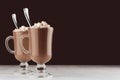 Elegant hot chocolate in two glass with marshmallows and silver spoon on dark brown background, copy space. Royalty Free Stock Photo