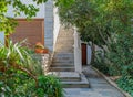 An elegant house garden and entrance stairway decorated with potted flowers.