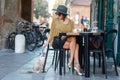 Elegant Italian woman with hat and glasses keeps her cat on a leash