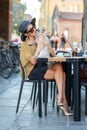 Elegant Italian woman with hat and glasses kisses her cat