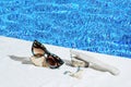 Elegant jewellery set of gold earrings and ring with blue topaz with sunglasses near swimming pool with transparent water as a