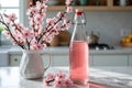 Elegant kitchen scene with cherry blossom vase and glass bottle of pink refreshment Royalty Free Stock Photo