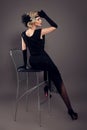 Elegant lady in black dress with retro hairstyle posing on studio black background. Beautiful blonde woman with long legs Royalty Free Stock Photo