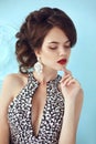 Elegant lady. Fashion beautiful girl model with red lips makeup, hairstyle and fashion earrings jewelry posing against the blue w Royalty Free Stock Photo