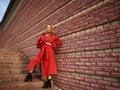 Elegant lady girl in coat terracotta colors posing on a city street on background of brick wall