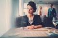 Elegant lady with glass of wine alone in restaurant