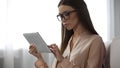 Elegant lady in glasses analyzing email letters, checking inbox folder on tablet Royalty Free Stock Photo