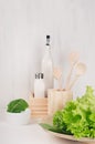 Elegant light kitchen interior with wooden utensils, ceramics and green leaves greens on white wood shelf. Royalty Free Stock Photo