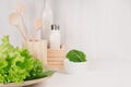 Elegant light kitchen interior with wooden utensils, ceramics and green leaves greens on white wood shelf. Royalty Free Stock Photo