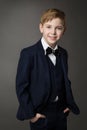 Elegant Little Boy in Classic Black Suit with Bowtie over Gray. Smiling Child Gentleman in Smart Casual Clothing. School Kids