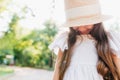 Elegant little lady wearing boater decorated with ribbon looking down and smiling. Close-up portrait of long-haired Royalty Free Stock Photo