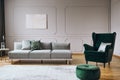 Elegant room interior with emerald green chair with pillow and long grey couch Royalty Free Stock Photo