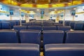 Elegant lounge for ferry passengers. View from the back of seats, visible screens and ceiling lights, blue chairs Royalty Free Stock Photo