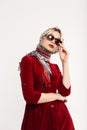 Elegant lovely young woman with sexy lips in fashionable sunglasses in red dress in leopard headscarf poses near vintage wall in Royalty Free Stock Photo