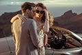 Elegant lovers posing next to the convertible