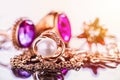 Elegant luxury composition of gold jewelry with pearl ring, amethysts and rubys gemstones on light background close-up macro and Royalty Free Stock Photo