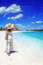 A elegant woman in a white dress walks down a tropical beach Royalty Free Stock Photo
