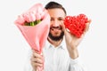Elegant man with a beard, with a bouquet of pink tulips and a red valentine heart, a gift for Valentine`s Day Royalty Free Stock Photo