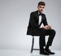 Elegant man in black tuxedo relaxing on metal chair Royalty Free Stock Photo