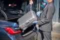 Elegant man putting suitcase inro trunk during pandemic