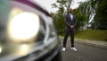 Elegant man in a suit without tie next to a car on the highway