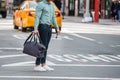 Elegant man walking on city street crosswalk wearing casual clothes with jeans ant t-shite and holding travel bag and sunglasses