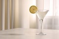 Elegant martini glass with fresh cocktail and lemon slice on beige marble table indoors. Space for text