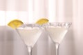 Elegant martini glasses with fresh cocktail and lemon slices near curtain