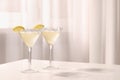 Elegant martini glasses with fresh cocktail and lemon slices on white table indoors. Space for text