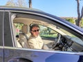 Elegant middle-aged man driving luxury blue car