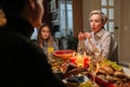 Elegant middle-aged mother-in-law celebrating Christmas with family, chatting at dinner holiday table in dark living Royalty Free Stock Photo
