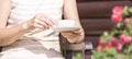 An elegant middle aged woman sits on a garden bench with a porcelain Cup in her hand Royalty Free Stock Photo