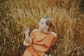 An elegant model lies on a wheat field enjoys nature. The concept of natural products, unity with nature, fashion. Beautiful young Royalty Free Stock Photo