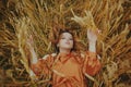 An elegant model lies on a wheat field enjoys nature. The concept of natural products, unity with nature, fashion. Beautiful young Royalty Free Stock Photo