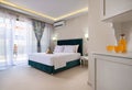 Elegant modern interior of bedroom in double suit hotel apartment with soft aquamarine textile bed and welcome fruity gift