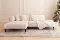 Elegant modern interior living room with large light  corner sofa. Comfortable couch with three cushions and a blanket standing in Royalty Free Stock Photo