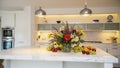 Elegant modern kitchen featuring a beautiful floral arrangement and fresh fruit display Royalty Free Stock Photo