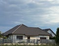 Elegant modern private single-family house with brown roof and metal fence.