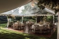 Elegant open air white tent for a wedding venue with hardwood floor and white formal furniture decor with flowers erected in a Royalty Free Stock Photo